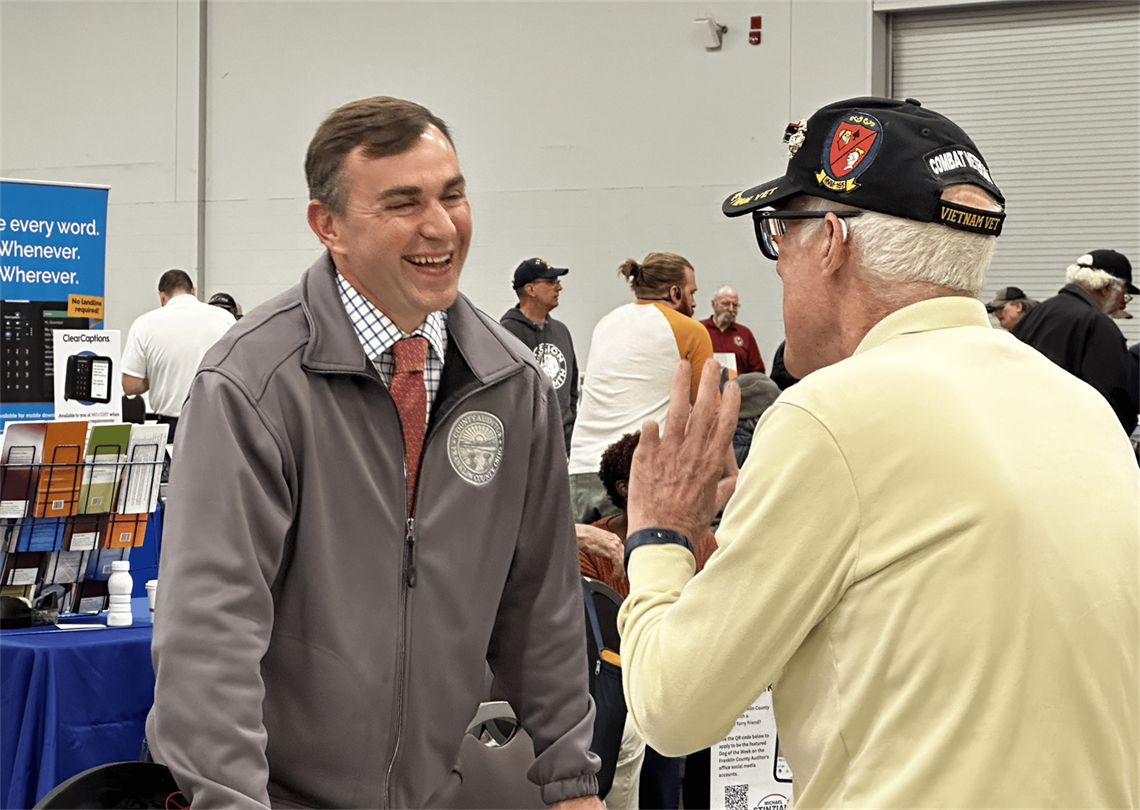 Photo of Auditor Stinziano laughing with a member of the community