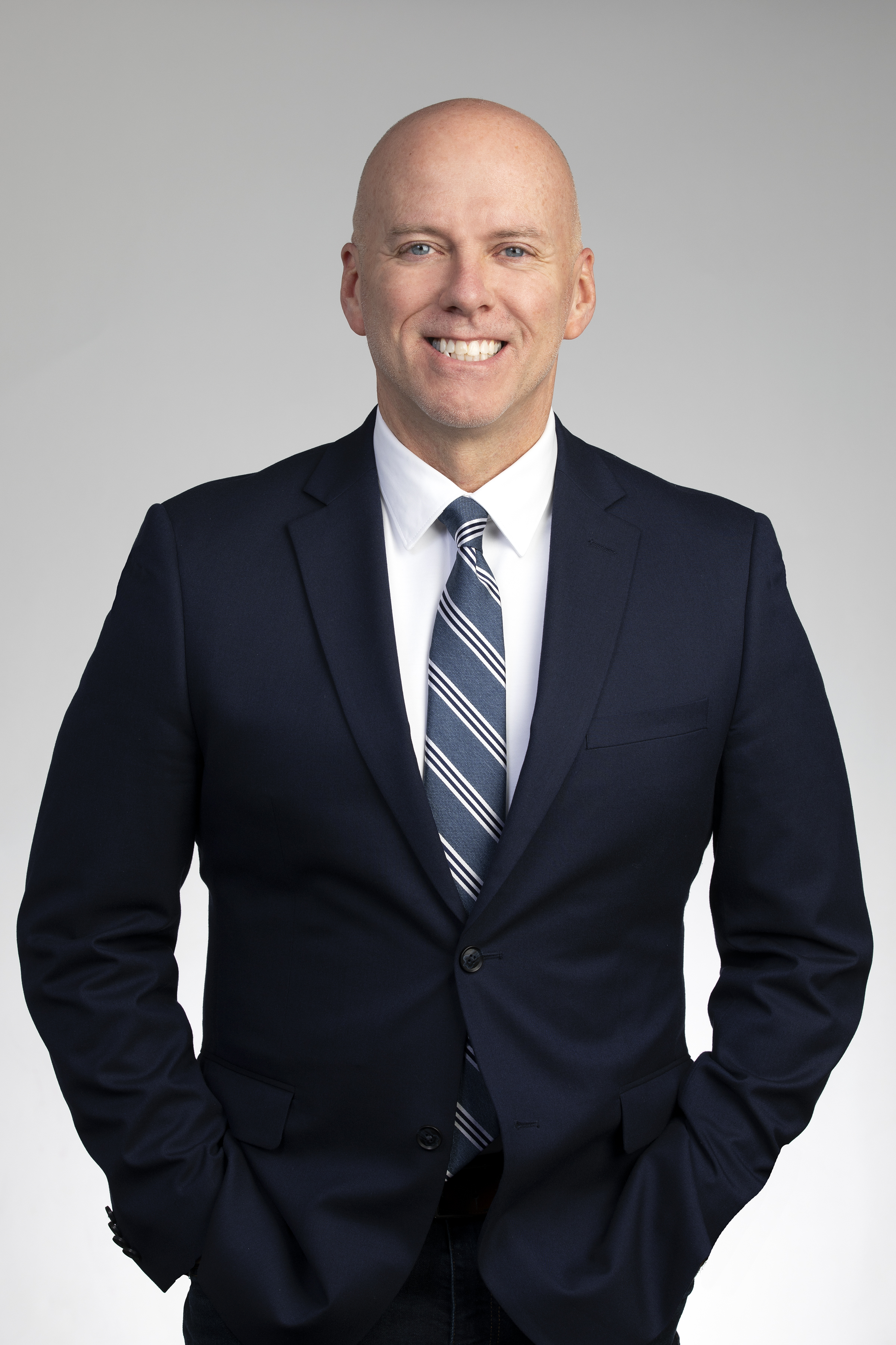 Mitch Williams in a dark colored suit smiling at the camera
